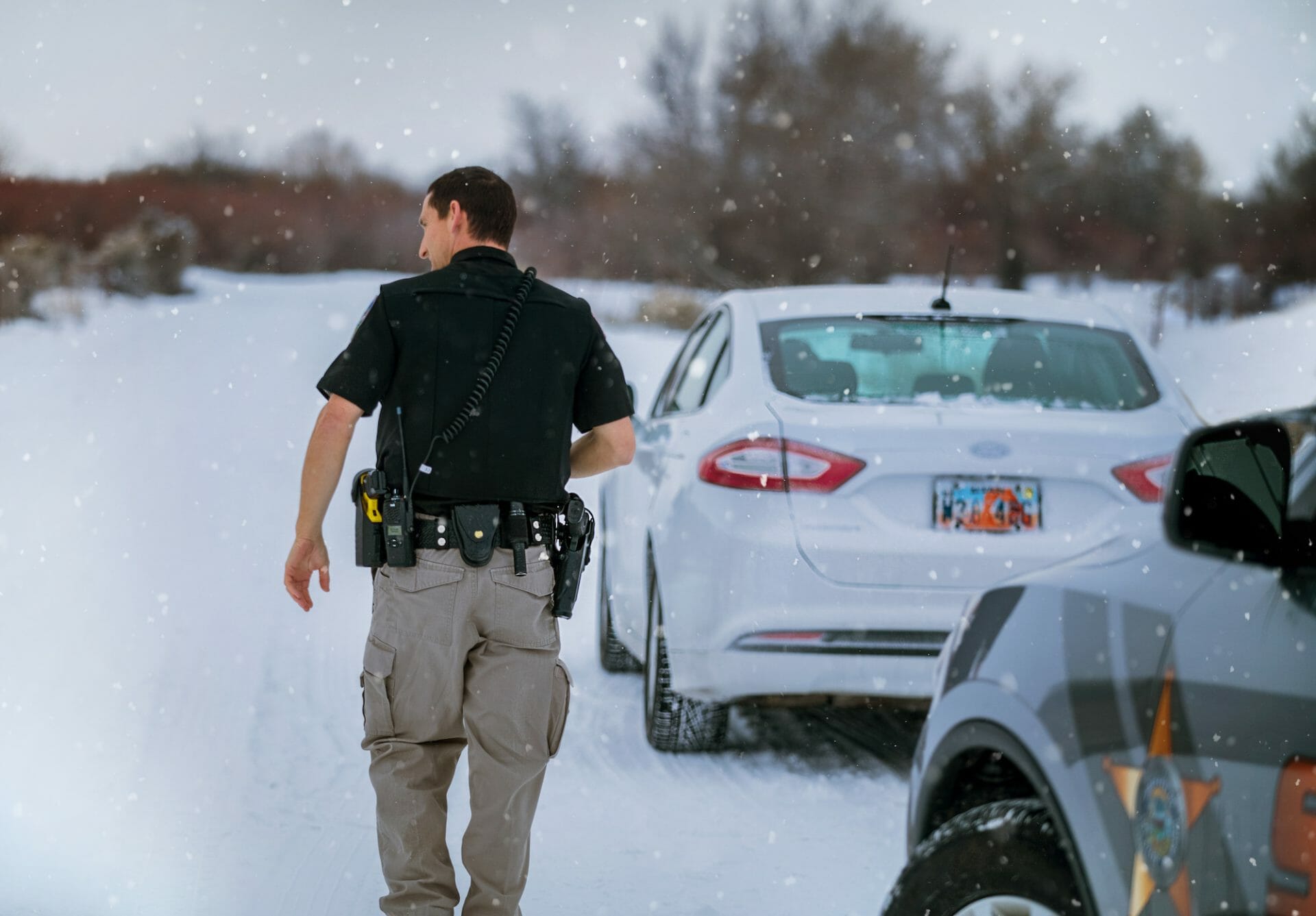 police officer walking towards pulled over vehicle in snow