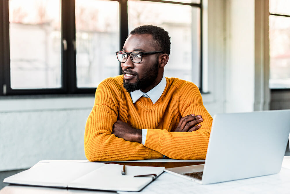 smiling african american businessman with crossed arms in office